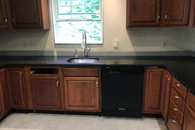 Inspiration for a mid-sized l-shaped enclosed kitchen remodel in Other with a single-bowl sink, raised-panel cabinets, medium tone wood cabinets, granite countertops, stainless steel appliances, no island and black countertops