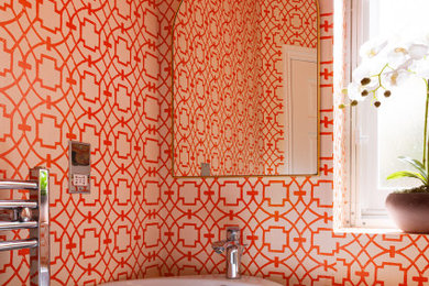 This is an example of a small eclectic cloakroom in London with orange walls and wallpapered walls.