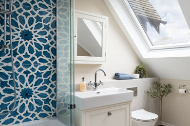 Inspiration for a medium sized farmhouse family bathroom in Berkshire with shaker cabinets, a built-in bath, a shower/bath combination, a wall mounted toilet, blue tiles, ceramic tiles, beige walls, porcelain flooring, an integrated sink, beige floors, a hinged door, a single sink and a floating vanity unit.
