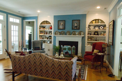 Mid-sized elegant enclosed medium tone wood floor and brown floor living room photo in Other with blue walls, a standard fireplace, a wood fireplace surround and no tv