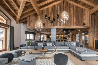 Aménagement d'un salon montagne ouvert avec un mur blanc, un sol en bois brun et un sol marron.