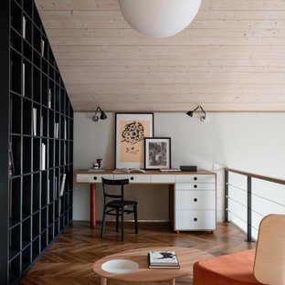 Modernes Arbeitszimmer mit weißer Wandfarbe, braunem Holzboden, freistehendem Schreibtisch, braunem Boden und Holzdielendecke in Sonstige