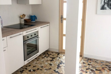 Aménagement d'une petite cuisine ouverte linéaire et encastrable contemporaine avec un évier 1 bac, un placard à porte plane, des portes de placard blanches, un plan de travail en bois, une crédence blanche, un sol en carrelage de céramique, aucun îlot, un sol beige et un plan de travail beige.