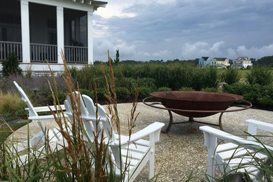 Design ideas for a mid-sized coastal partial sun backyard mulch landscaping in Other with a fire pit.