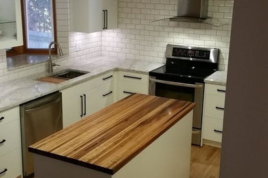 Inspiration for a mid-sized transitional brown floor kitchen remodel in Other with an undermount sink, flat-panel cabinets, white cabinets, wood countertops, white backsplash, subway tile backsplash, stainless steel appliances and an island