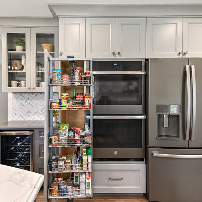Eat-in kitchen - huge country l-shaped medium tone wood floor and brown floor eat-in kitchen idea in Milwaukee with a farmhouse sink, shaker cabinets, gray cabinets, quartz countertops, white backsplash, marble backsplash, stainless steel appliances, an island and gray countertops