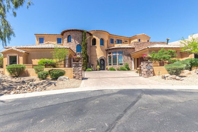 Large southwestern orange two-story stucco house exterior idea in Phoenix with a tile roof