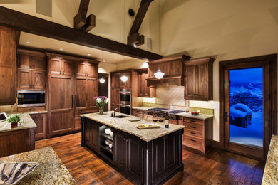 Example of a huge classic u-shaped medium tone wood floor eat-in kitchen design in Denver with flat-panel cabinets, medium tone wood cabinets, an island, granite countertops, green backsplash, glass tile backsplash, paneled appliances and a single-bowl sink