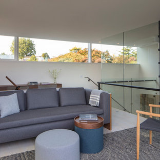 This is an example of a modern study in Seattle with white walls, light hardwood flooring, a two-sided fireplace, a wooden fireplace surround, a freestanding desk and white floors.