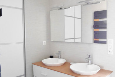 Aménagement d'une salle de bain blanche et bois méditerranéenne avec des portes de placard blanches, un carrelage gris, meuble double vasque et meuble-lavabo encastré.