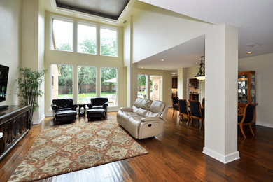 This is an example of a large traditional open concept living room in Houston with beige walls, medium hardwood floors, no fireplace and no tv.