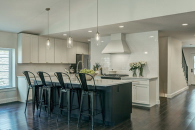 Inspiration for a mid-sized timeless single-wall dark wood floor and brown floor kitchen remodel in St Louis with shaker cabinets, white cabinets, granite countertops, white backsplash, subway tile backsplash, stainless steel appliances and an island