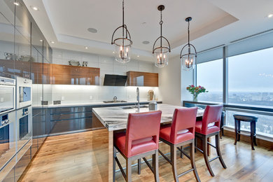 Enclosed kitchen - contemporary u-shaped medium tone wood floor enclosed kitchen idea in Calgary with flat-panel cabinets, gray cabinets, marble countertops, stainless steel appliances and an island
