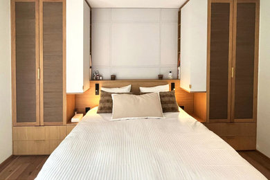 Imagen de dormitorio principal y blanco y madera actual de tamaño medio sin chimenea con paredes beige, suelo de madera oscura, suelo marrón, casetón y boiserie