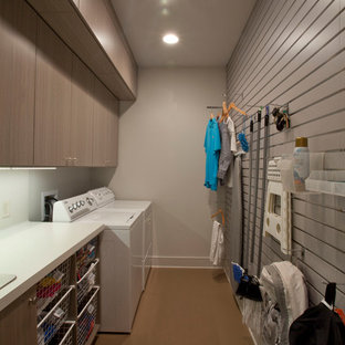 ニューオリンズのモダンスタイルのおしゃれなランドリールーム (ドロップインシンク、ラミネートカウンター、グレーの壁、コルクフローリング、左右配置の洗濯機・乾燥機) の写真