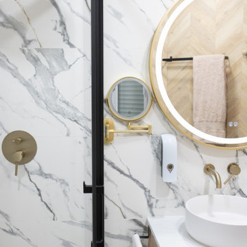 Contrastes elegantes en baño con detalles dorados y cerramientos negros