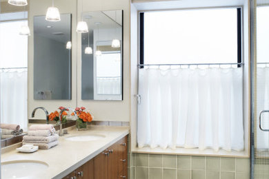 Bathroom - large transitional master green tile double-sink bathroom idea in New York with flat-panel cabinets, medium tone wood cabinets, solid surface countertops, beige countertops and a built-in vanity
