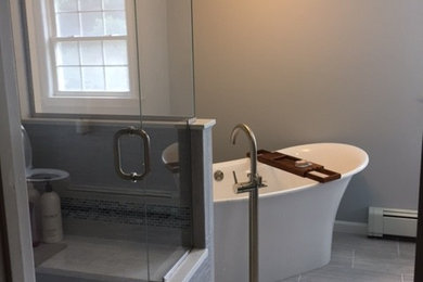 На фото: большая главная ванная комната в стиле модернизм с отдельно стоящей ванной, угловым душем, серой плиткой, серыми стенами и душем с распашными дверями с