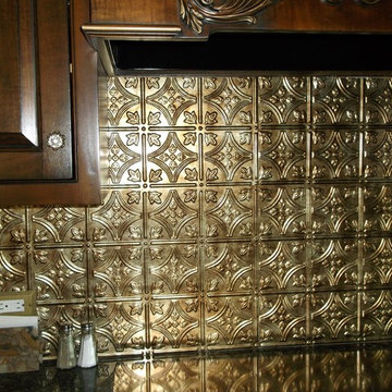 Detail of tin backsplash with gold cooktop in foreground