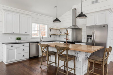 Example of a mid-sized farmhouse l-shaped dark wood floor eat-in kitchen design in Indianapolis with an undermount sink, shaker cabinets, white cabinets, granite countertops, shiplap backsplash, stainless steel appliances, an island and black countertops