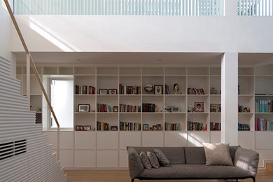 This is an example of a modern loft-style family room in Singapore with a library, white walls, bamboo floors, no fireplace and a freestanding tv.