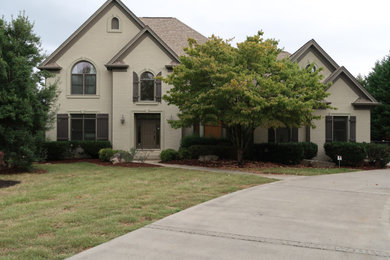 Photo of a large and beige modern two floor brick detached house in Other with a pitched roof, a shingle roof and a brown roof.