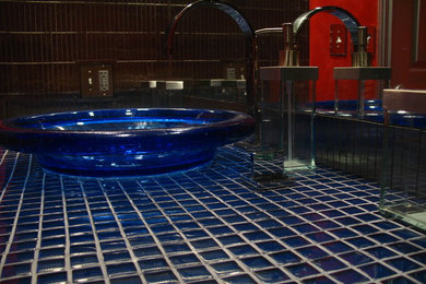 Diseño de cuarto de baño moderno grande con baldosas y/o azulejos azules, baldosas y/o azulejos de vidrio, paredes rojas, aseo y ducha, lavabo sobreencimera y encimera de vidrio