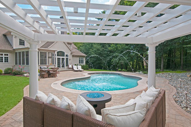 Design ideas for a backyard custom-shaped pool in Boston with a water feature and stamped concrete.