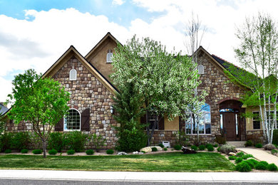This is an example of a large one-storey beige house exterior in Denver with stone veneer.