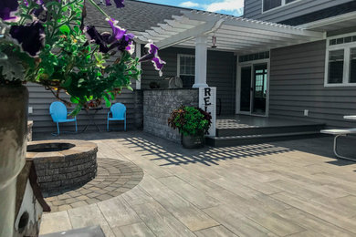 Backyard stone patio photo in Other with a fire pit and a pergola