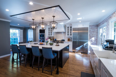 Inspiration for a large 1960s l-shaped medium tone wood floor and beige floor eat-in kitchen remodel in Los Angeles with a farmhouse sink, raised-panel cabinets, white cabinets, quartz countertops, white backsplash, marble backsplash, stainless steel appliances, an island and white countertops