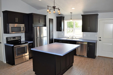L-shaped light wood floor open concept kitchen photo in Other with black cabinets, stainless steel appliances and an island