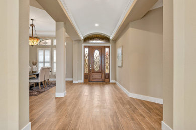 Example of a large trendy porcelain tile and brown floor foyer design in Orange County with beige walls