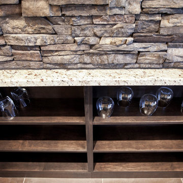 Stone basement wetbar and dark wood cabinetry