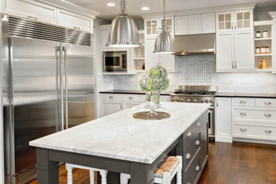 Mid-sized trendy medium tone wood floor and brown floor kitchen photo in Los Angeles with recessed-panel cabinets, white cabinets, quartzite countertops, gray backsplash, marble backsplash, stainless steel appliances and an island