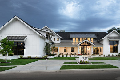 This is an example of a country two-storey white house exterior in Boise with mixed siding, a gable roof and a mixed roof.