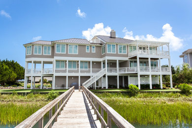 Large beach style three-storey brown house exterior in Wilmington with wood siding, a hip roof and a metal roof.