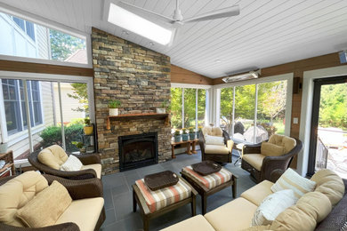 Example of a large mountain style slate floor and gray floor sunroom design in Philadelphia with a standard fireplace, a stacked stone fireplace and a skylight