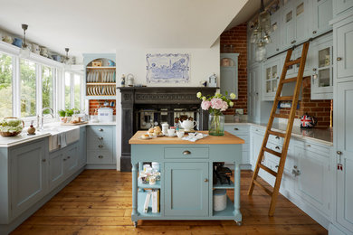 Design ideas for a large country u-shaped eat-in kitchen in Other with a farmhouse sink, shaker cabinets, blue cabinets, quartzite benchtops, medium hardwood floors, with island, red splashback, brick splashback and brown floor.