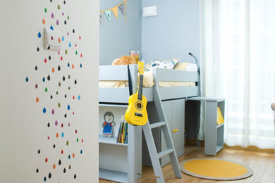 Mid-sized contemporary gender-neutral kids' bedroom in Paris with light hardwood floors and blue walls for kids 4-10 years old.