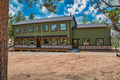 Large minimalist green two-story stone house exterior photo in Denver with a butterfly roof, a shingle roof and a black roof