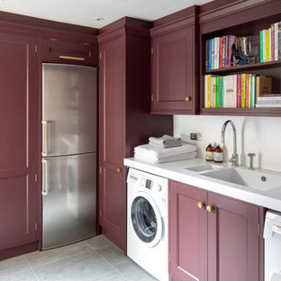 ケントの中サイズのトランジショナルスタイルのおしゃれな家事室 (一体型シンク、落し込みパネル扉のキャビネット、赤いキャビネット、白い壁、左右配置の洗濯機・乾燥機、グレーの床、白いキッチンカウンター) の写真