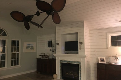 Design ideas for a mid-sized beach style enclosed family room in Philadelphia with white walls, dark hardwood floors, a standard fireplace, a stone fireplace surround and a freestanding tv.