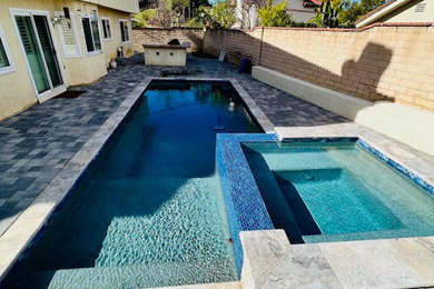 Example of a classic backyard brick and rectangular natural hot tub design in Los Angeles