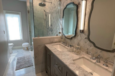Mid-sized elegant kids' white tile and marble tile marble floor, white floor and double-sink bathroom photo in Chicago with raised-panel cabinets, gray cabinets, a two-piece toilet, gray walls, an undermount sink, marble countertops, a hinged shower door, white countertops, a niche and a freestanding vanity