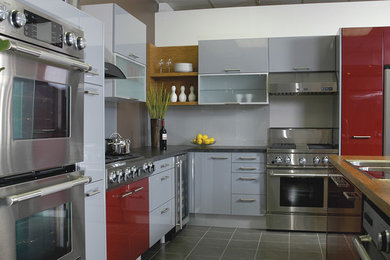 Example of a mid-sized trendy single-wall slate floor and gray floor eat-in kitchen design in Toronto with a double-bowl sink, flat-panel cabinets, gray cabinets, solid surface countertops, gray backsplash, stone slab backsplash, stainless steel appliances and an island