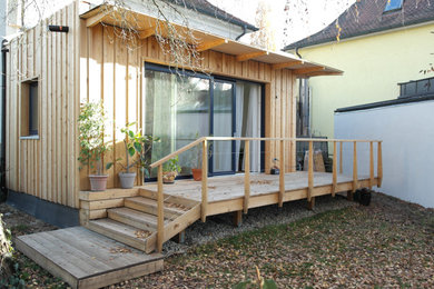 Modelo de terraza planta baja de estilo americano de tamaño medio en patio trasero y anexo de casas con barandilla de madera