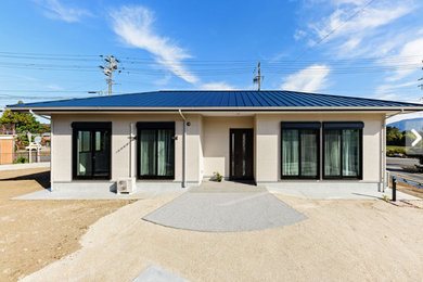 Foto de fachada de casa beige y azul de una planta con tejado a cuatro aguas