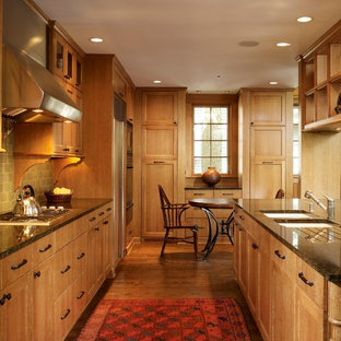 Diseño de cocina de galera, contemporánea, grande, abierta, con armarios con paneles empotrados, puertas de armario de madera oscura, fregadero de doble seno, encimera de granito, salpicadero gris, electrodomésticos de acero inoxidable, suelo de madera en tonos medios, una isla y salpicadero de azulejos de terracota