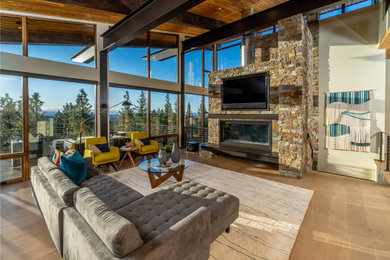 This is an example of a large rustic open plan living room in Other with white walls, light hardwood flooring, a ribbon fireplace, a stone fireplace surround, a wall mounted tv and a vaulted ceiling.